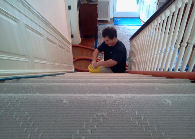 A person cleaning carpeted stairs