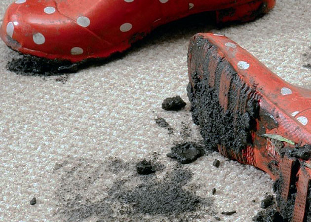 A pair of muddy boots on carpet