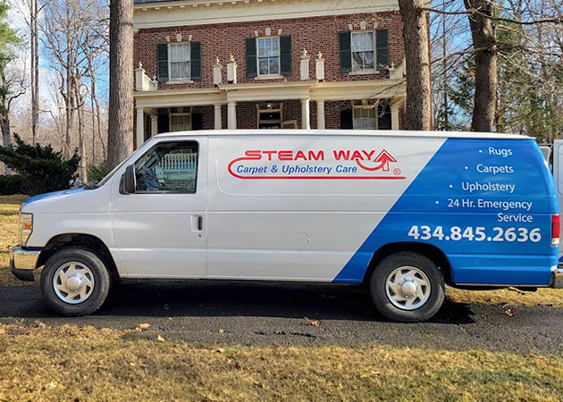 A van parked on a street in front of a brick house